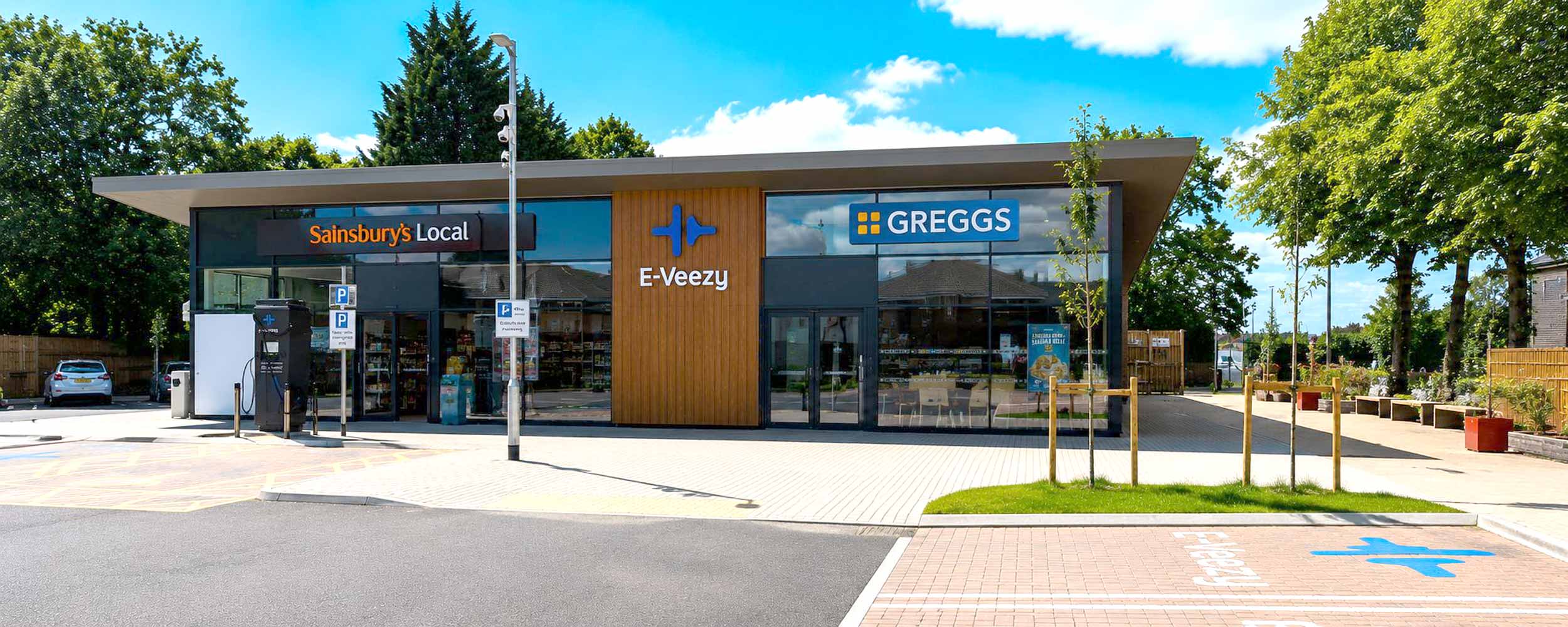 Modern roadside service area with EV charging canopy, parked fleet vehicles, and Northwood Park amenities signage.