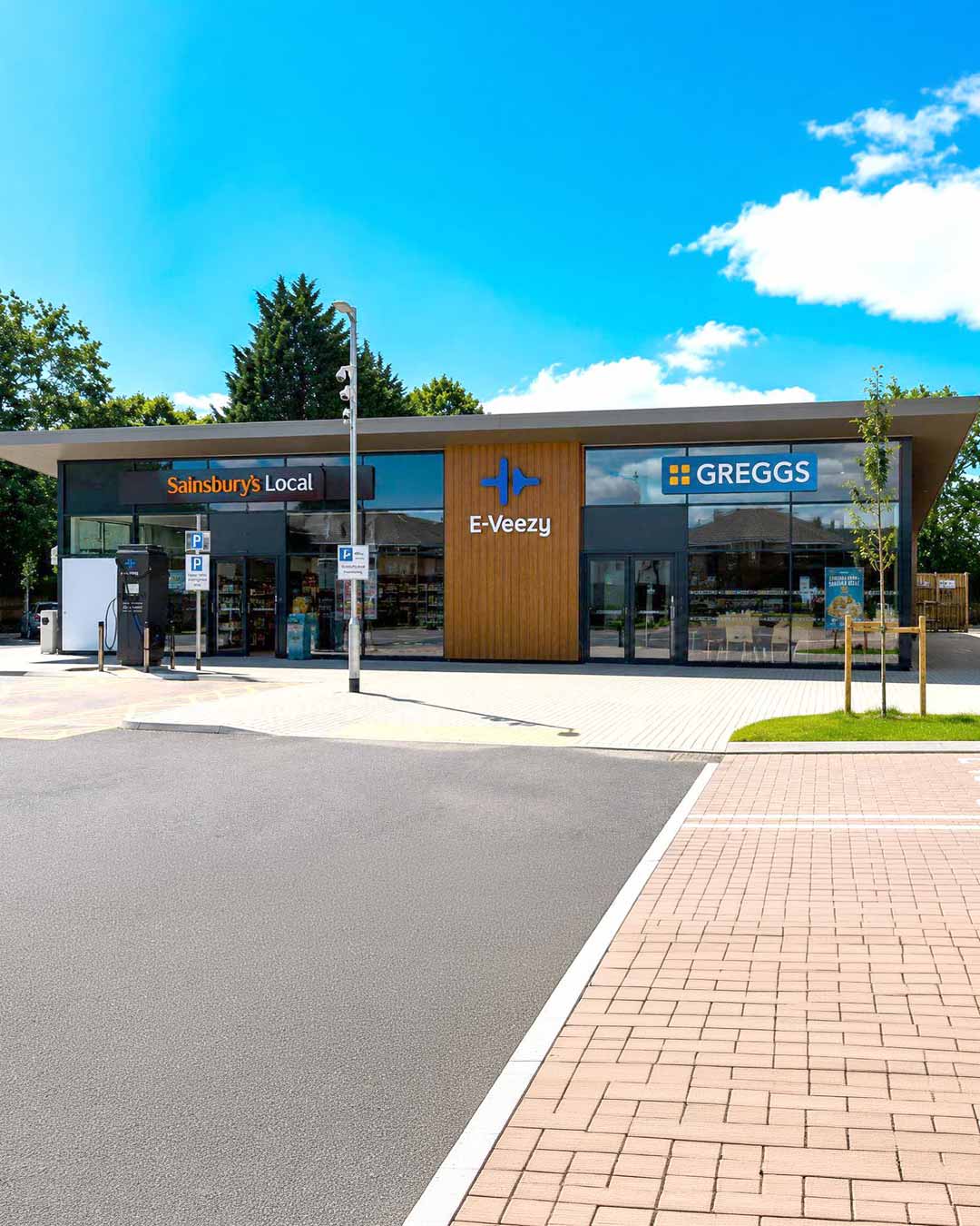 Modern roadside service area with EV charging canopy, parked fleet vehicles, and Northwood Park amenities signage.